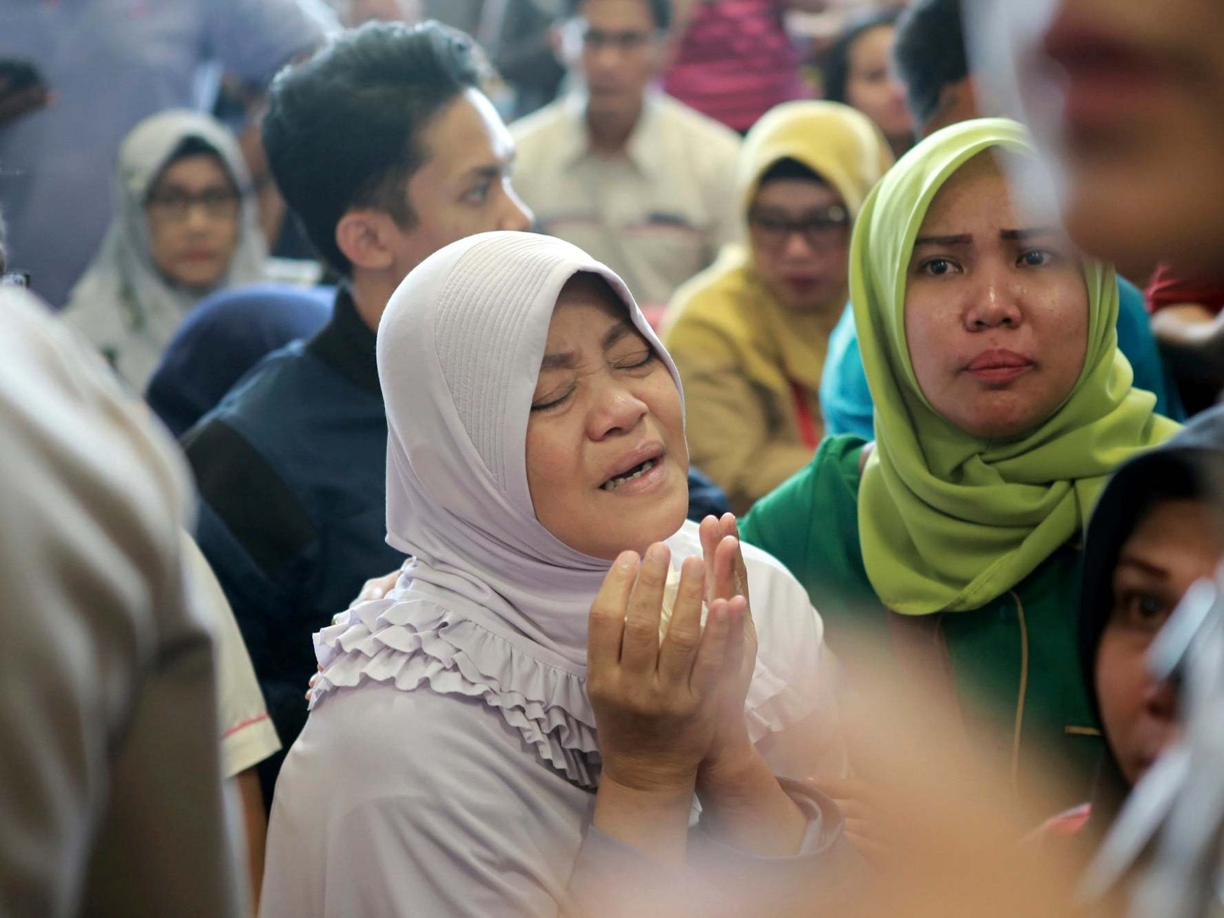 Relatives praying while waiting for news about the Lion Air flight; all 189 passengers and crew were killed in the crash