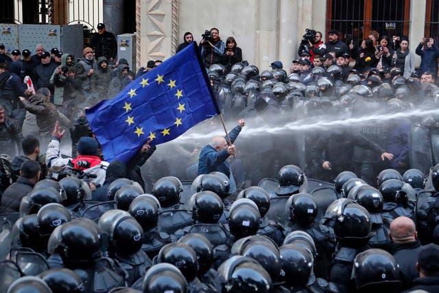 Riot police disperse opposition supporters during a protest rally in front of the parliament building in Tbilisi