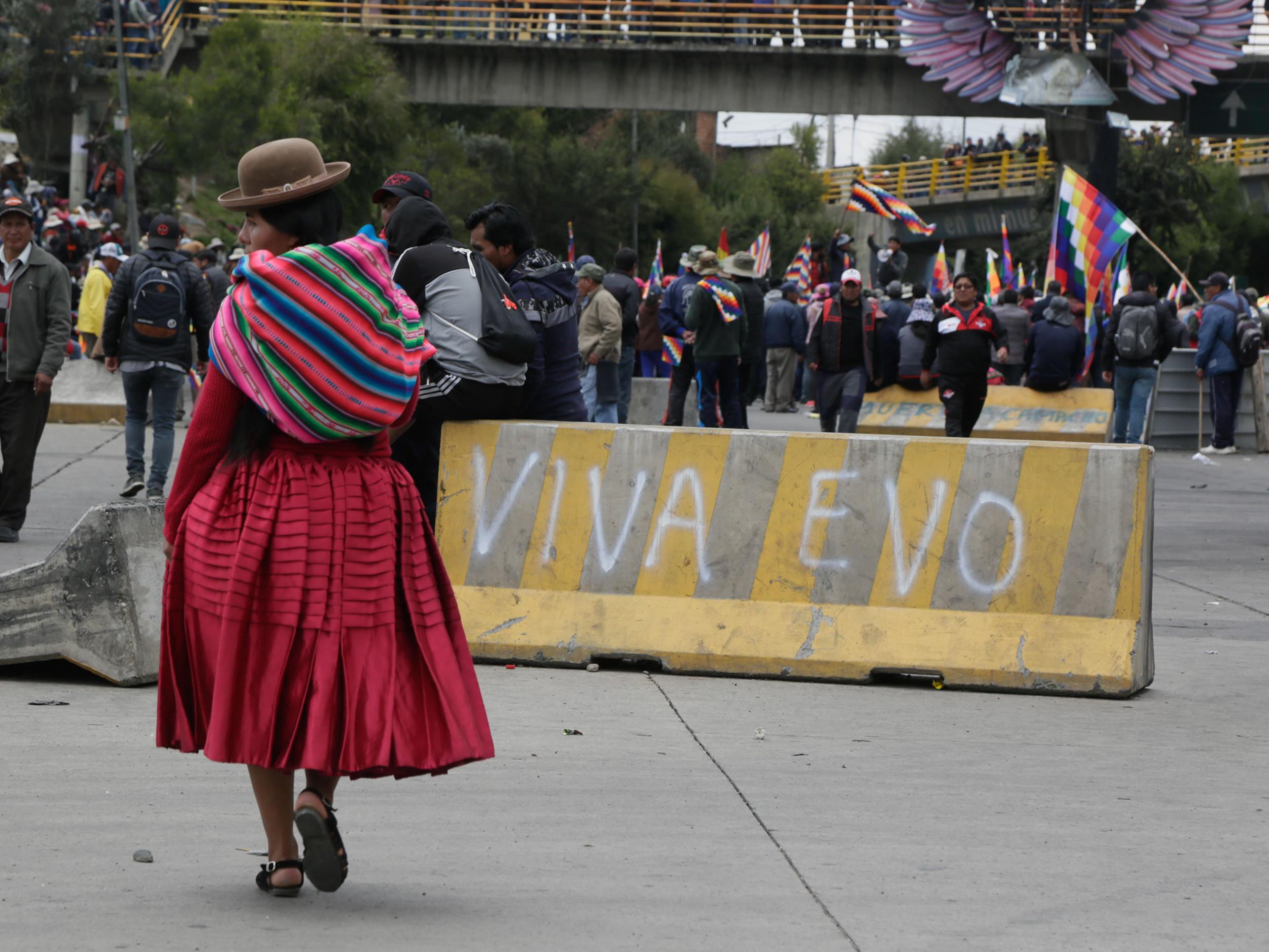 A supporter walks in front of graffiti that reads ‘Long live Evo’​ during a protest