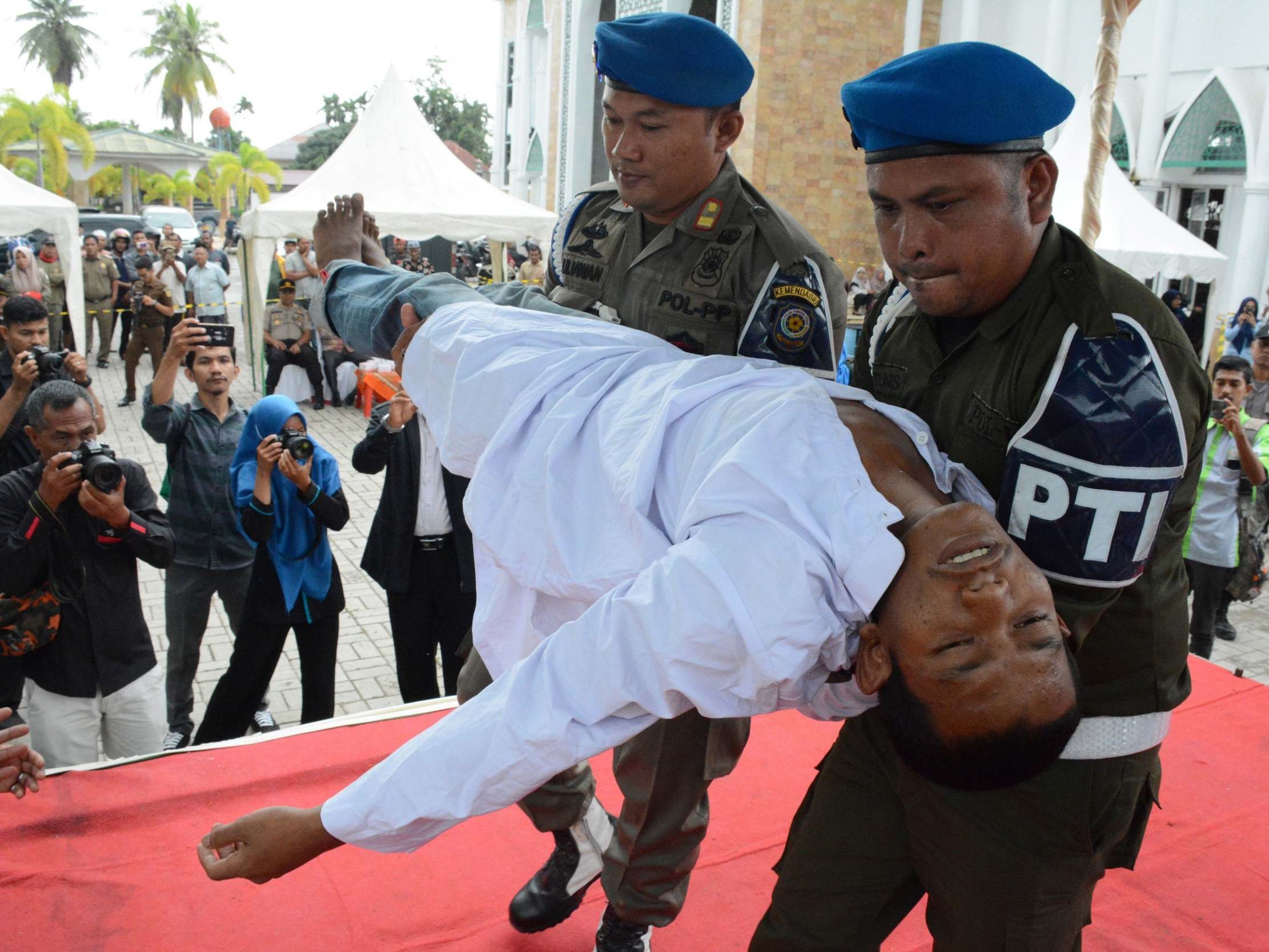 Indonesian women wait to be whipped in front of a baying crowd for