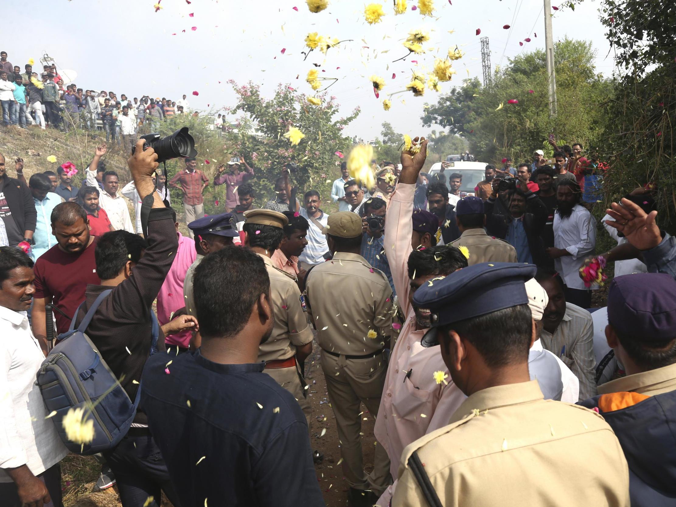 People throw flower petals on the Indian policemen guarding the area where rape accused were shot in Shadnagar on 6 December