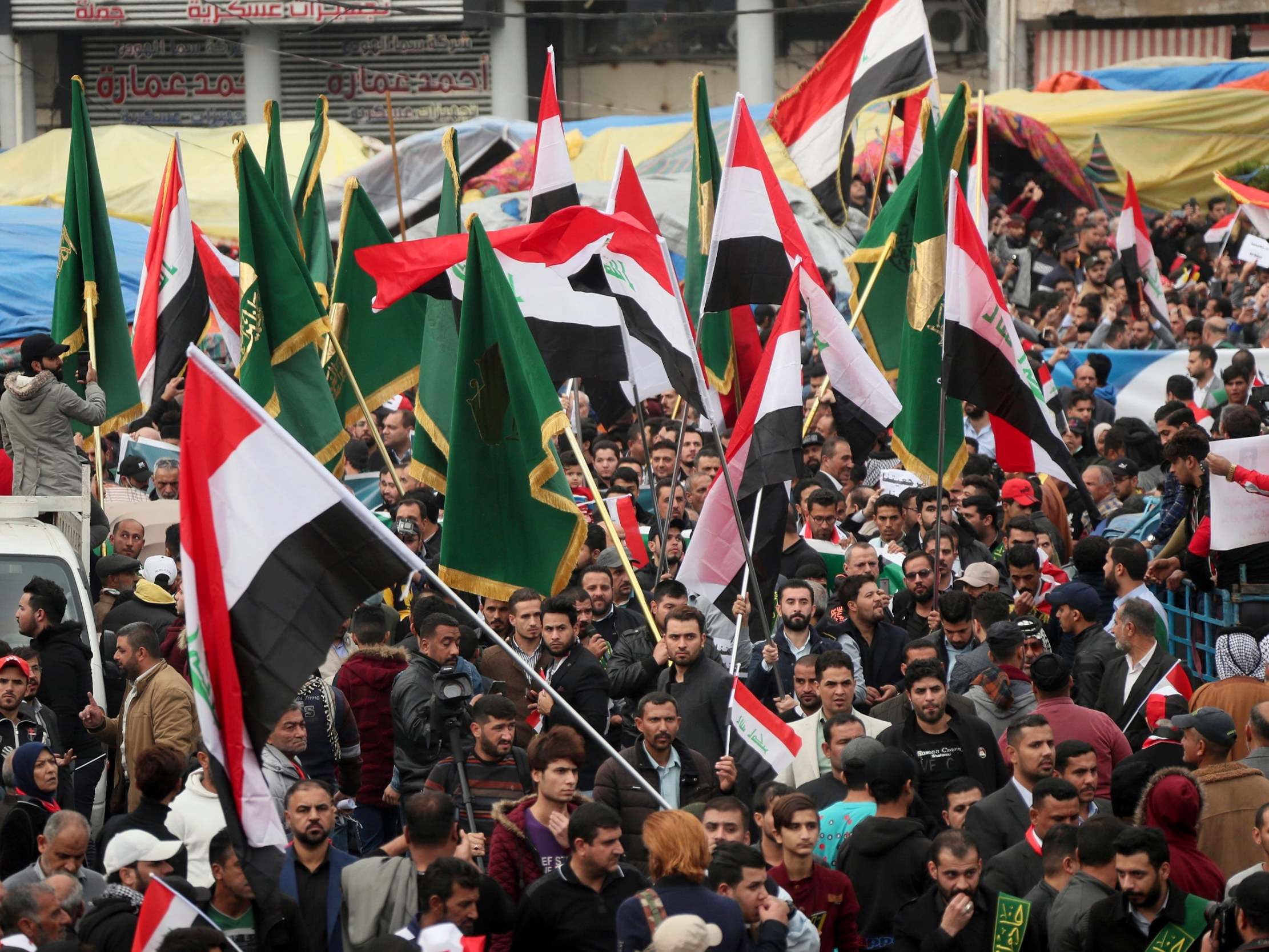 Protesters hold Popular Mobilisation Forces (PMF) and Iraqi flags as they march towards Tahrir Square in Baghdad, Iraq, 6 December, 2019.