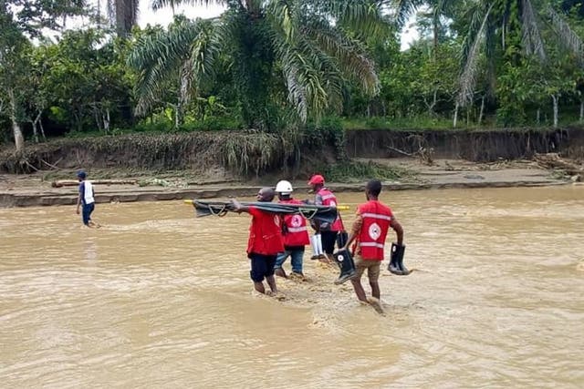 Members of the Ugandan Red Cross carry a dead body after flooding and landslides left 16 dead in western Uganda