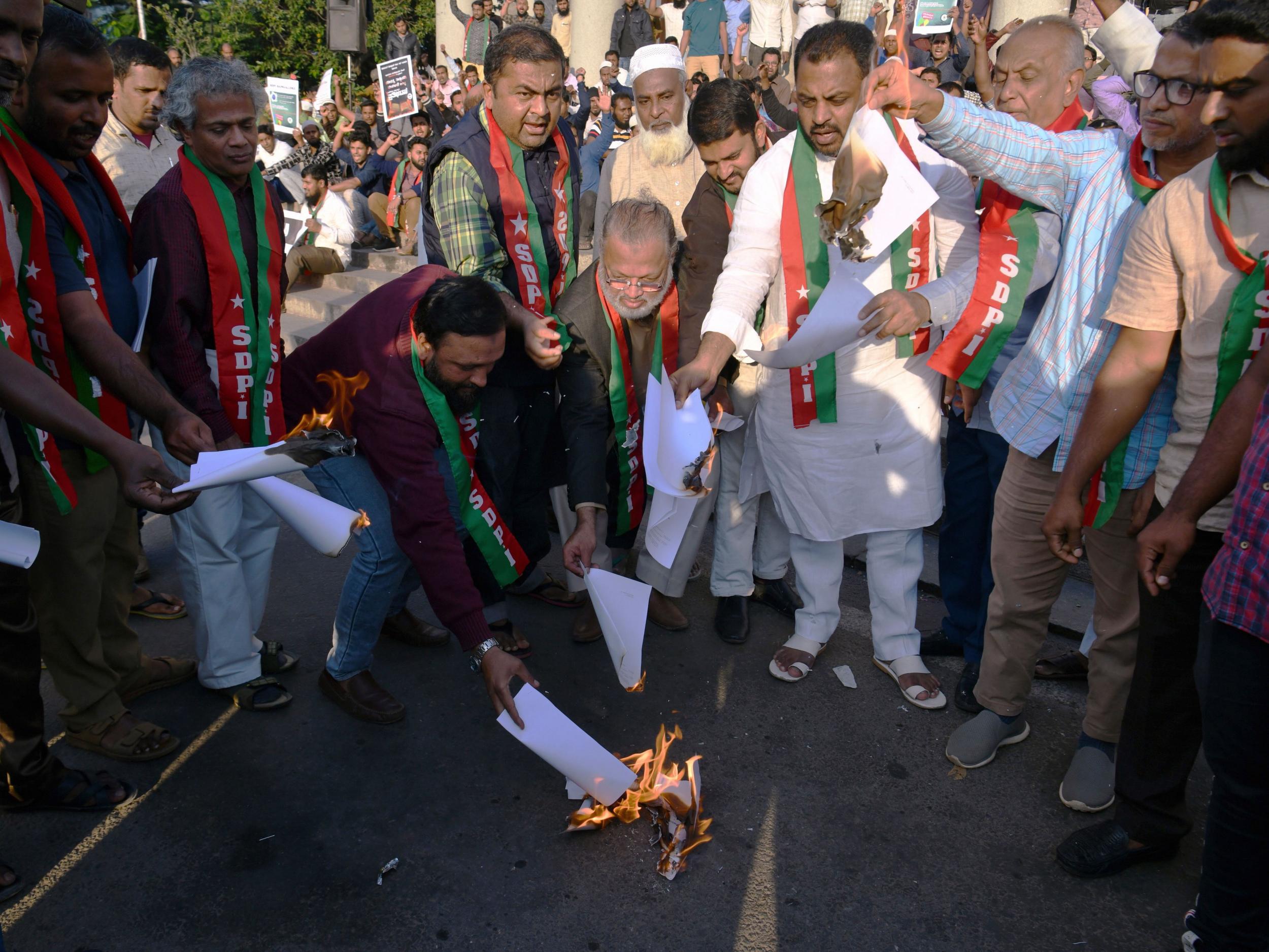 Members and activists shout slogans against the Indian government as they burn copies of the Citizenship Amendment Bill 2019
