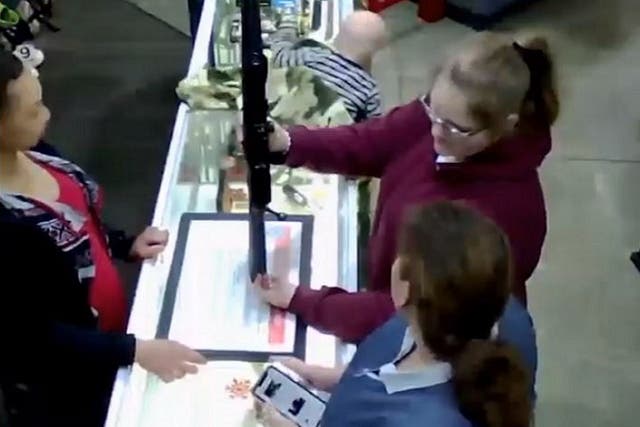 Still image from CCTV footage of a baby falling off a counter at Family Pawn in Utah, US, while two women look at a rifle.
