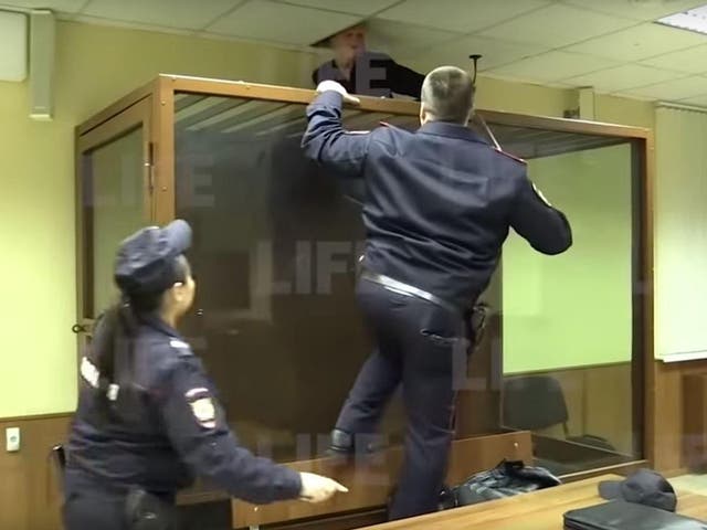 Russian police try to stop criminal Leonid Greyser, 18, from escaping through the ceiling of the courtroom