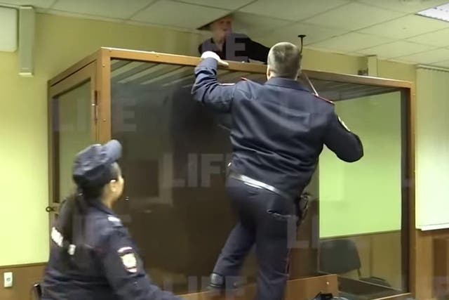 Russian police try to stop criminal Leonid Greyser, 18, from escaping through the ceiling of the courtroom