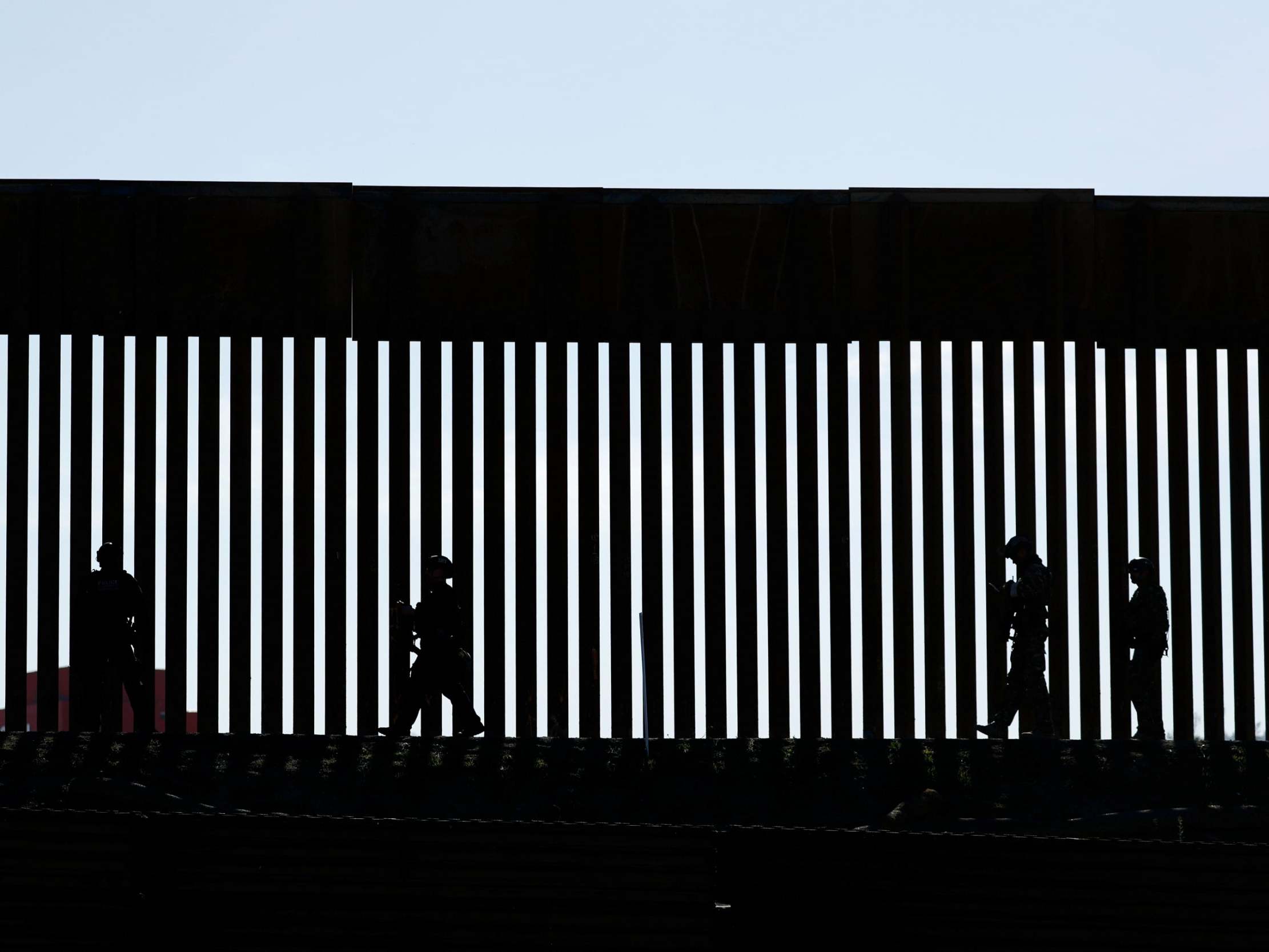 Silhouettes against the US-Mexico border fence