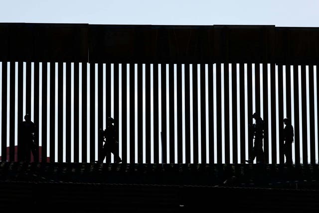 Silhouettes against the US-Mexico border fence