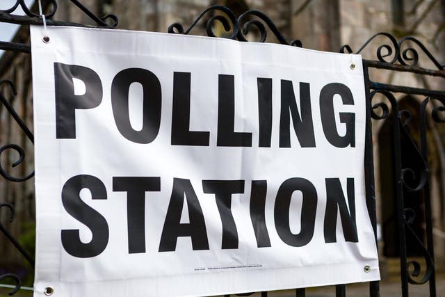 A vinyl polling station banner tied to railings with a church door visible in the background