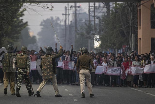 Indian police and paramilitary personnel stop protesters during a curfew in Gauhati