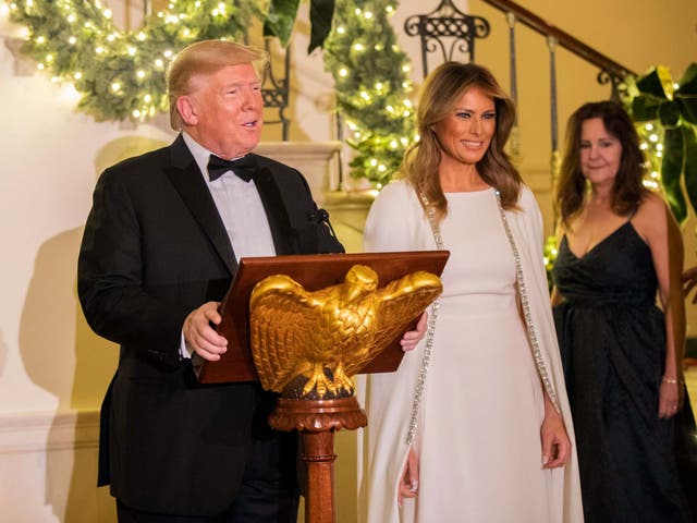 President Donald Trump, flanked by first lady Melania Trump, speaks in the Grand Foyer of the White House during the Congressional Ball on 12 December 2019