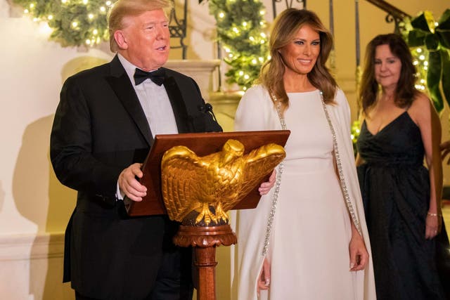 President Donald Trump, flanked by first lady Melania Trump, speaks in the Grand Foyer of the White House during the Congressional Ball on 12 December 2019