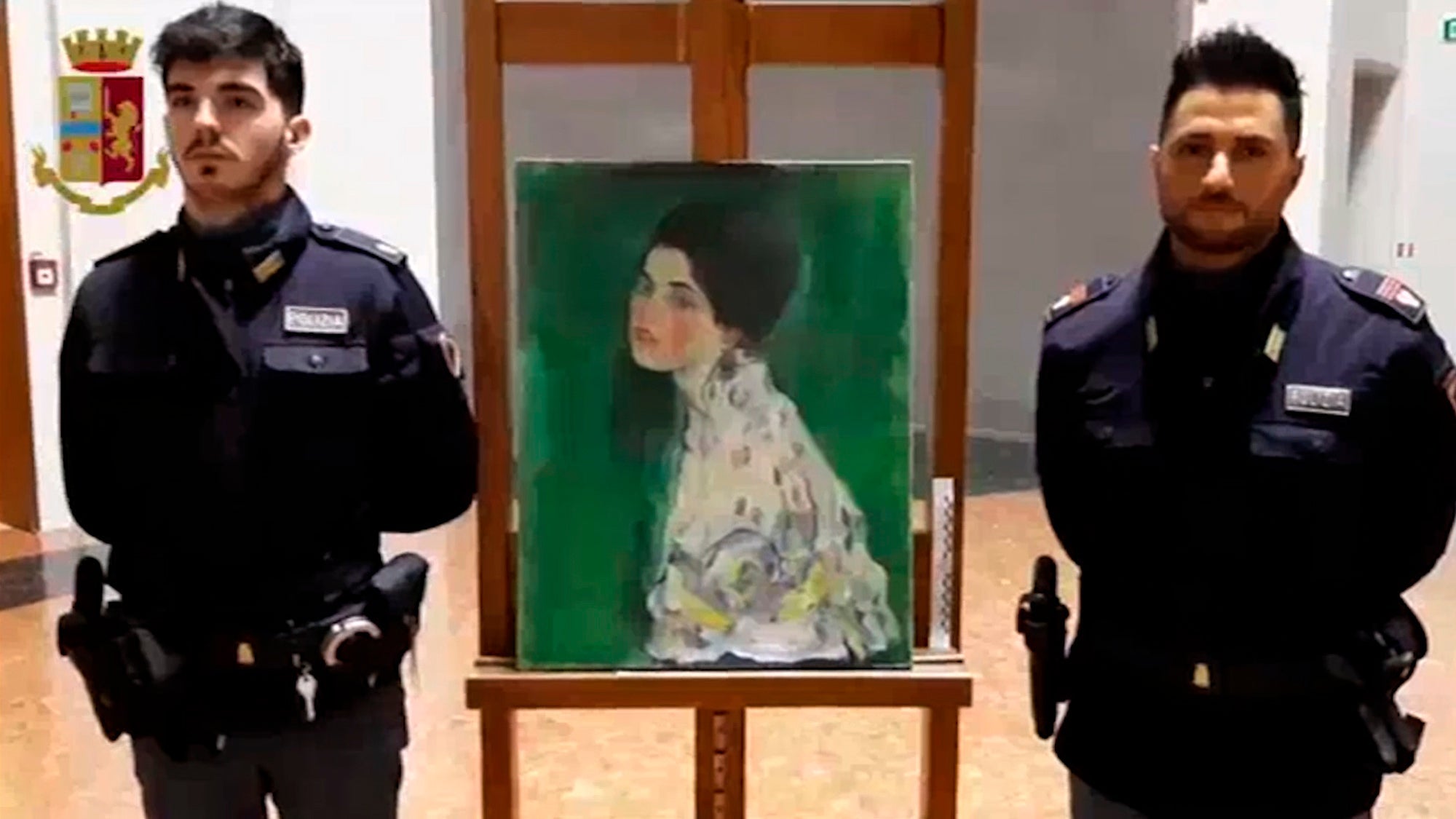 Two police officers stand guard next to a painting – believed to be a stolen artwork by Gustav Klimt – discovered in a cavity in a gallery's walls, in Piacenza, northern Italy