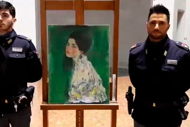 Two police officers stand guard next to a painting – believed to be a stolen artwork by Gustav Klimt – discovered in a cavity in a gallery's walls, in Piacenza, northern Italy