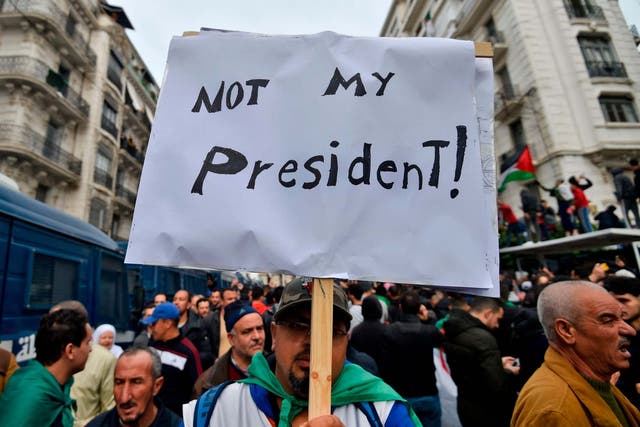 An Algerian protester lifts a placard in the capital Algiers during a demonstration against the election results