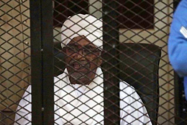 Sudan's ousted president Omar al-Bashir sits in the defendant's cage during his trial