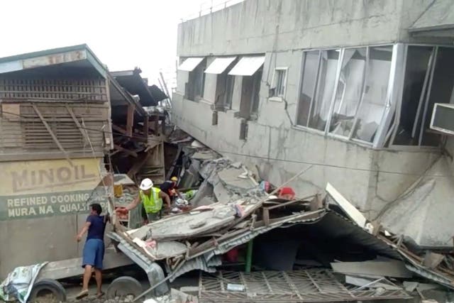 Rescue crew members look for trapped victims at a collapsed building at Padada market in Padada, Philippines, on 15 December 15 2019