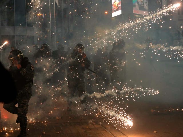 Lebanese riot policemen react to firecrackers that fired by the supporters of the Shiite Hezbollah and Amal Movement groups, as they try to attack the anti-government protesters in Beirut
