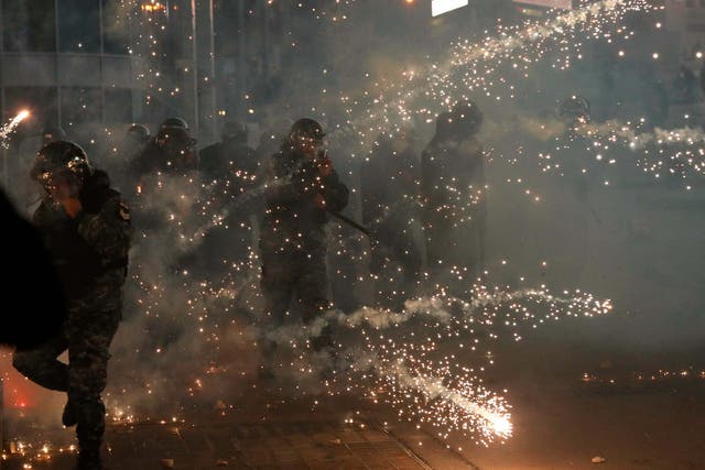 Lebanese riot policemen react to firecrackers that fired by the supporters of the Shiite Hezbollah and Amal Movement groups, as they try to attack the anti-government protesters in Beirut