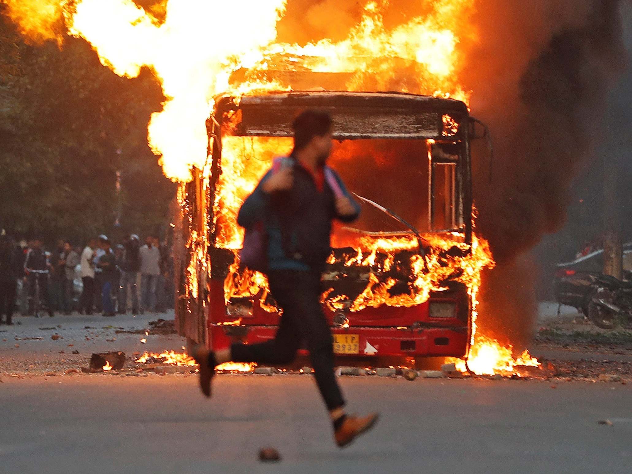 A man runs past a burning bus in New Delhi, India