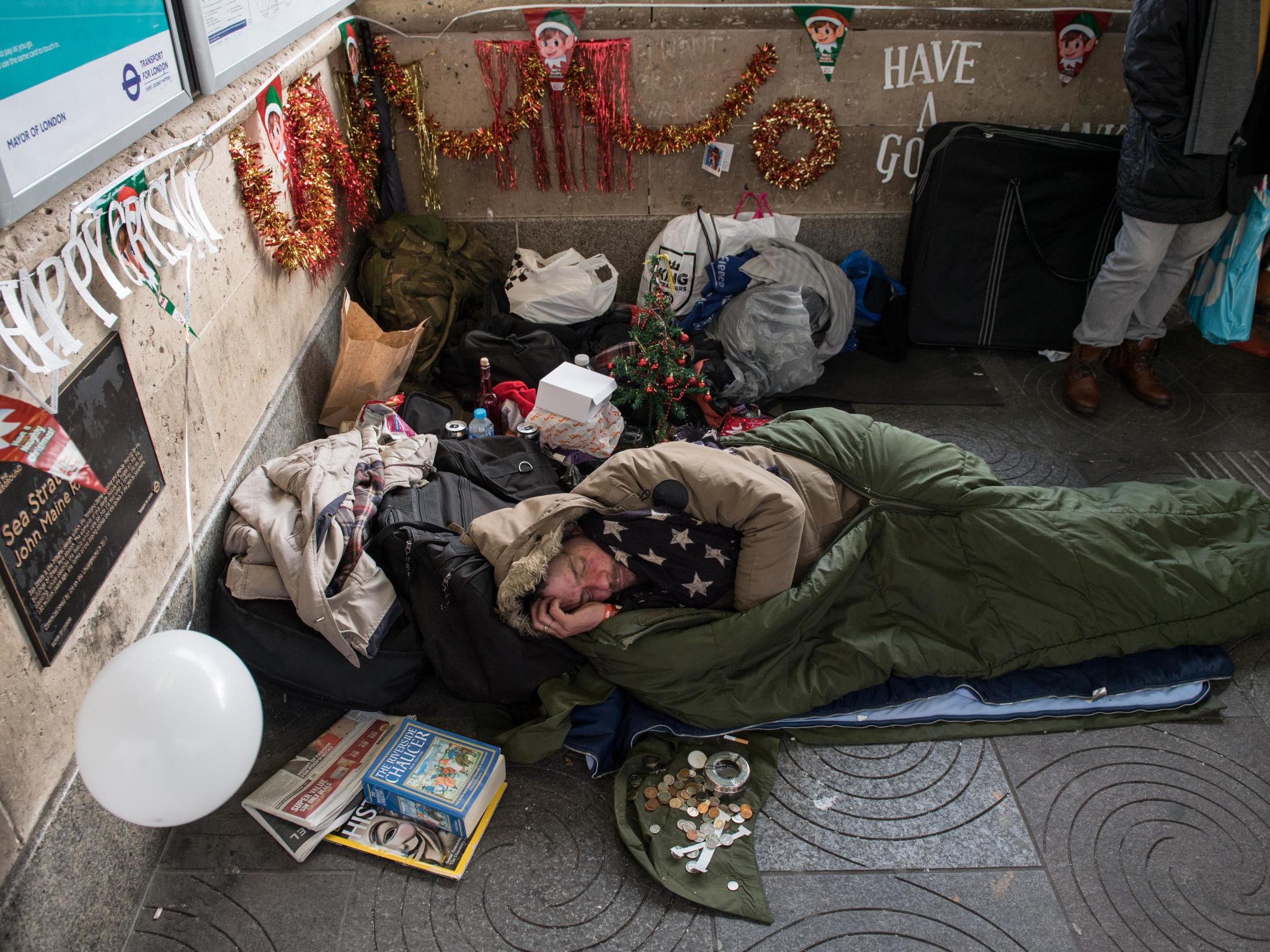 A homeless man sleeps outside Green Park station in London