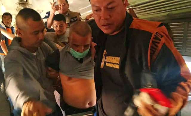Thai police officers escort Somkid Poompuang after his arrest at the Pak Chong train station in Nakhon Ratchasima province