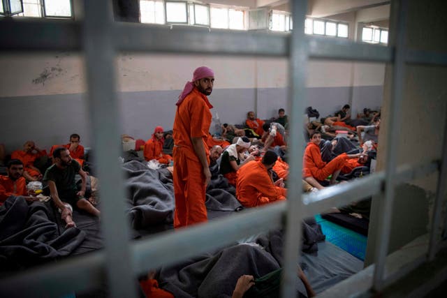 Men allegedly affiliated with Isis sit on the floor in a prison in northeastern Syria