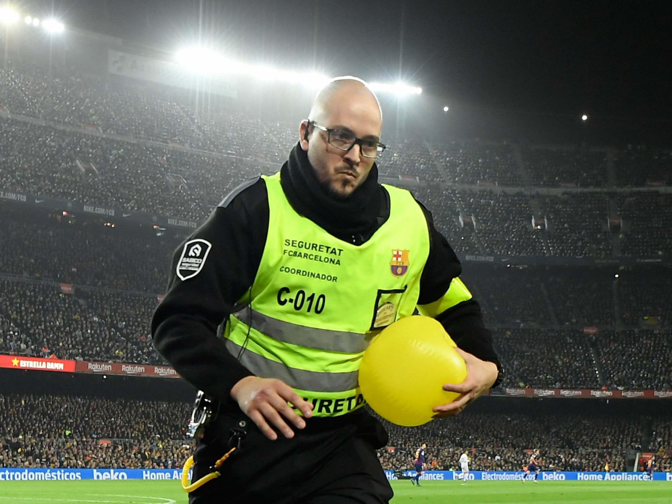 A steward helps to clear the pitch during a protest at El Clasico
