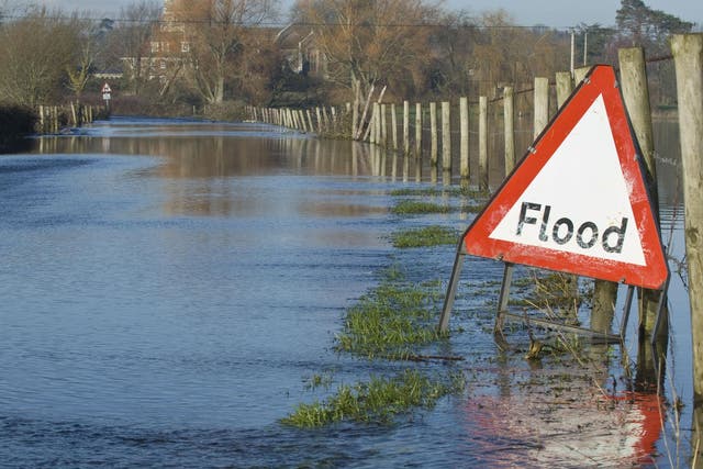 A flood warning sign, on a closed country road next to water logged fields in the Avon Valley, Hampshire