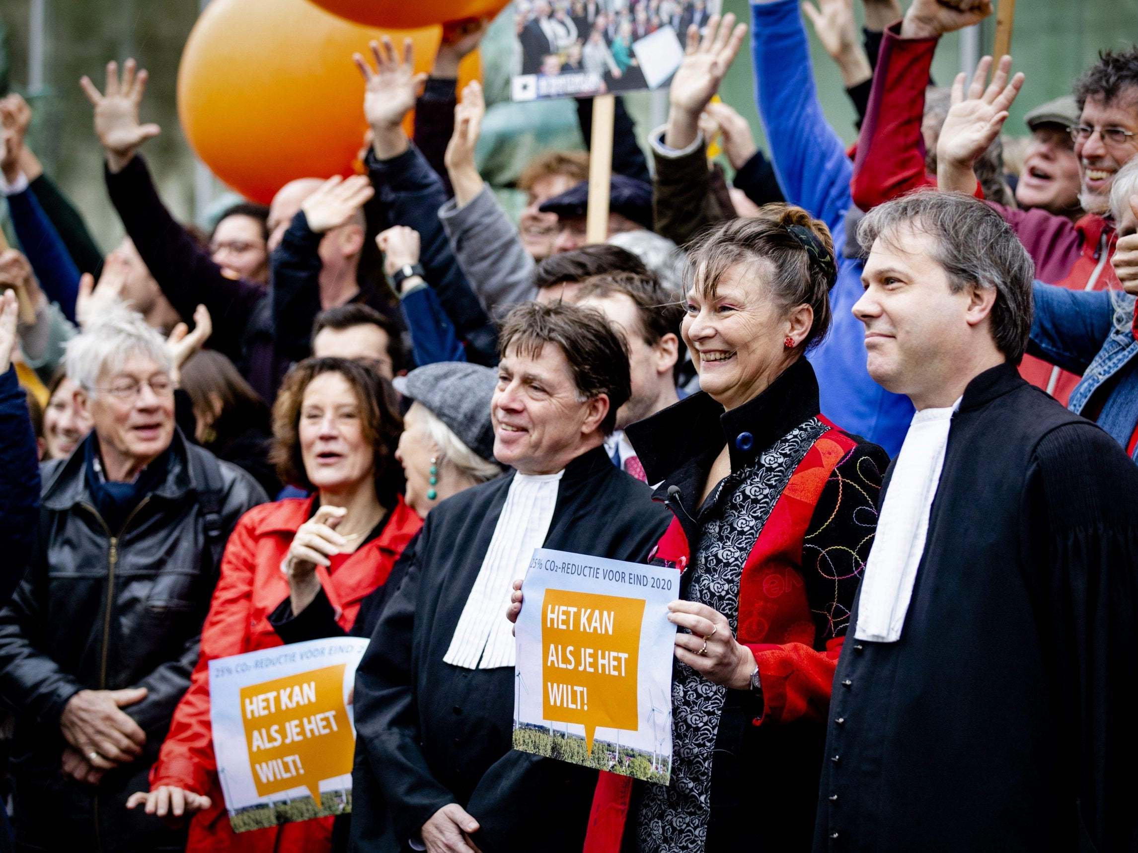Marjan Minnesma (second on right), director of environment NGO Urgenda, holds a banner outside the Supreme Court prior its ruling in the Urgenda case on 20 December in The Hague