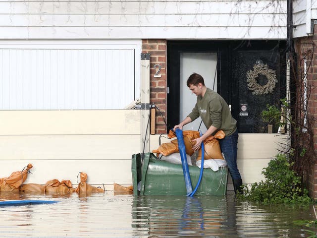 A man attempts to pump water out of his home in Yalding, Kent, after the area flooded following heavy rain