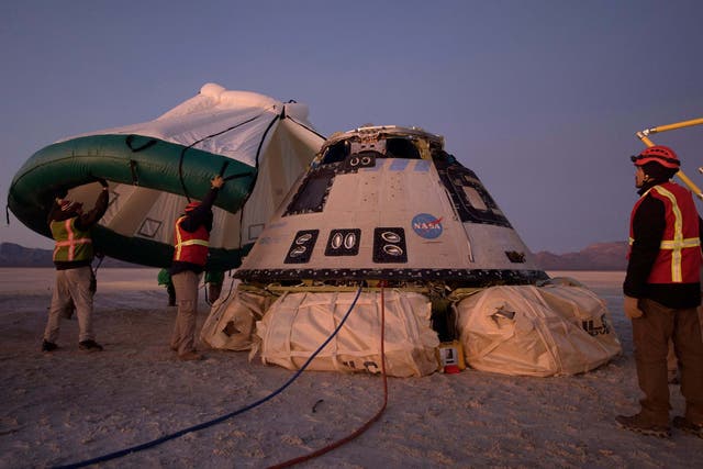 Boeing, NASA, and US Army personnel work around the Boeing Starliner spacecraft shortly after it landed in White Sands, New Mexico, 22 December, 2019.