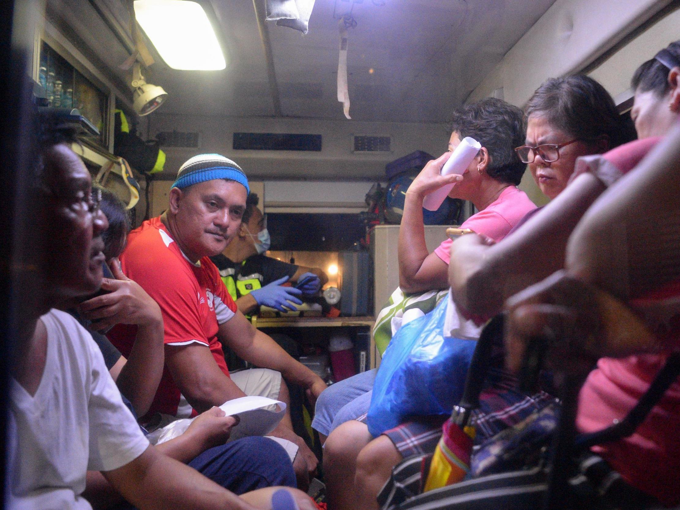 Residents who fell ill after drinking a coconut wine called lambanog sit in an ambulance as they wait to be transferred from the Philippine General Hospital to another Manila hospital