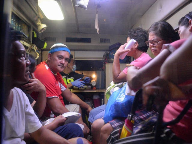 Residents who fell ill after drinking a coconut wine called lambanog sit in an ambulance as they wait to be transferred from the Philippine General Hospital to another Manila hospital