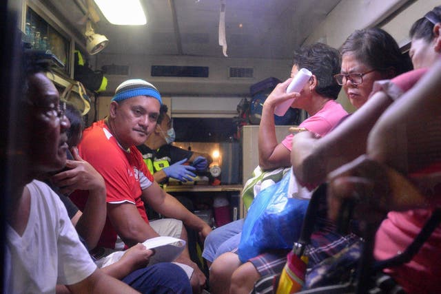 Residents who fell ill after drinking a coconut wine called lambanog sit in an ambulance as they wait to be transferred from the Philippine General Hospital to another Manila hospital