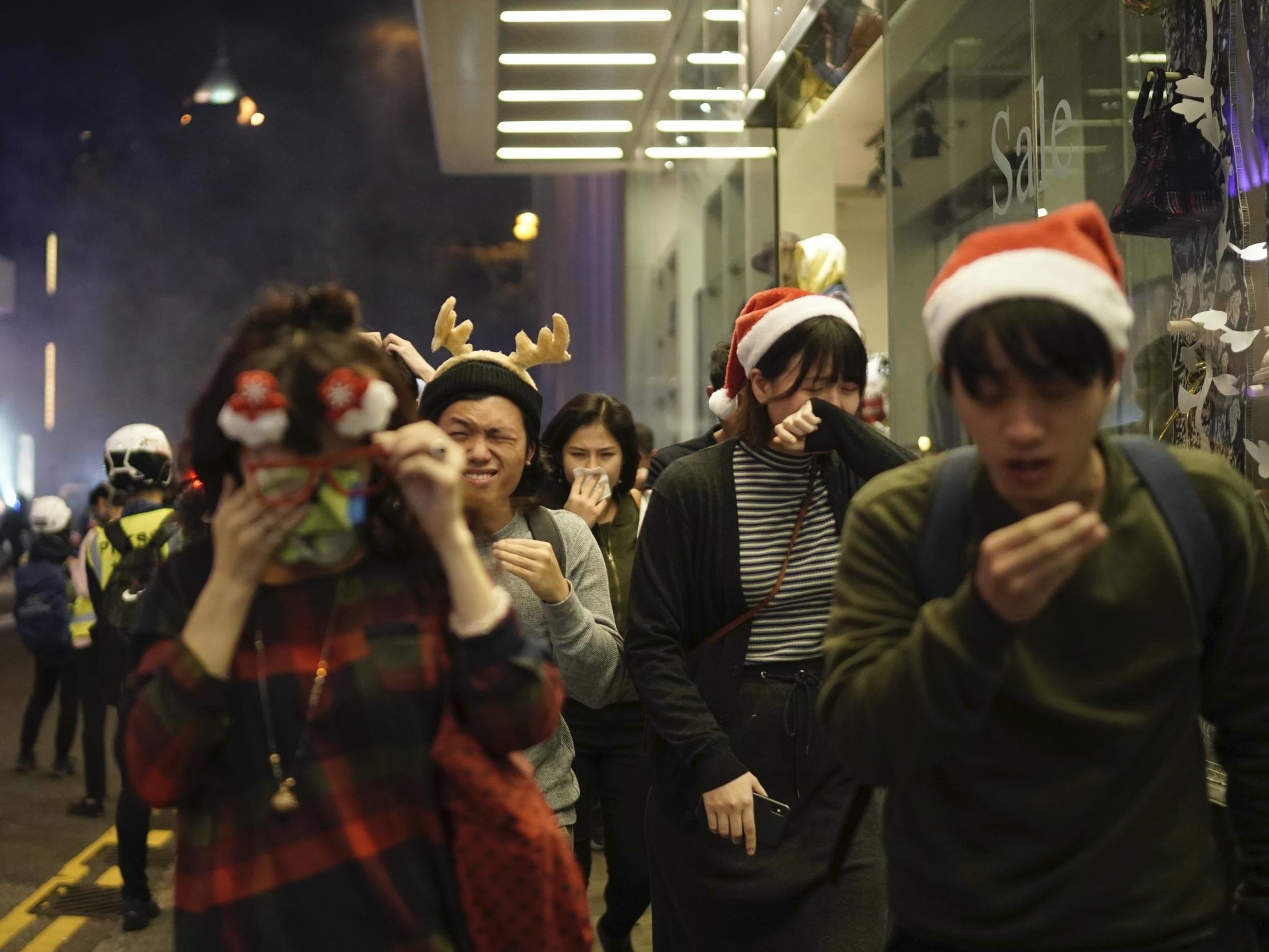Residents dressed for Christmas festivities react to tear gas as police confront protesters on Christmas Eve in Hong Kong