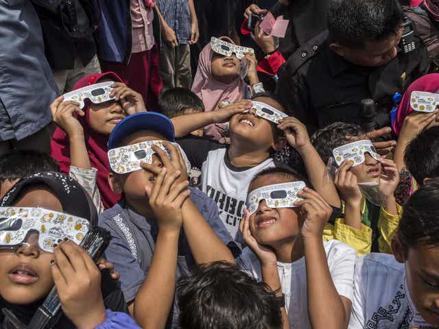 Children watch the moon move in front of the sun in a rare "ring of fire" solar eclipse in Surabaya, Indonesia