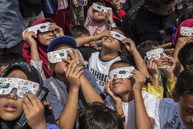 Children watch the moon move in front of the sun in a rare "ring of fire" solar eclipse in Surabaya, Indonesia