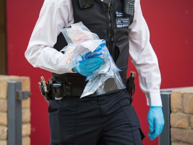 Police officer carries an evidence bag after a number of drugs raids in south London