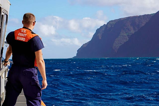 A member of the US Coast Guard Cutter moves toward the Na Pali Coast on the Hawaiian island of Kauai
