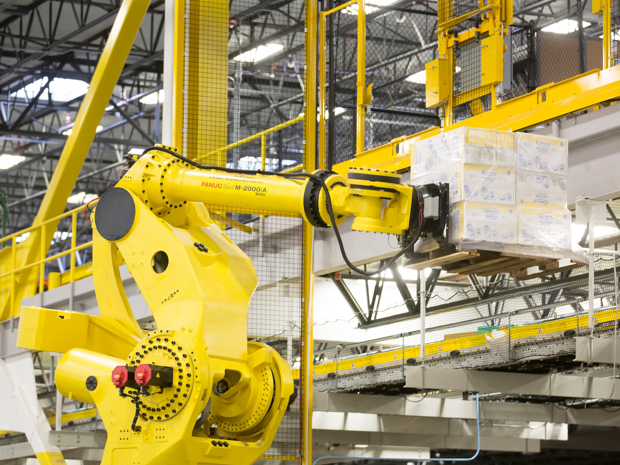 A robotic arm lifts a pallet of merchandise inside an Amazon Fulfillment Center