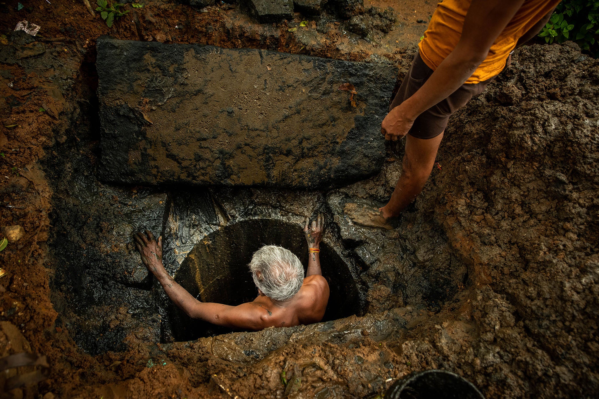 Kaverappa inspects a pit of toilet waste