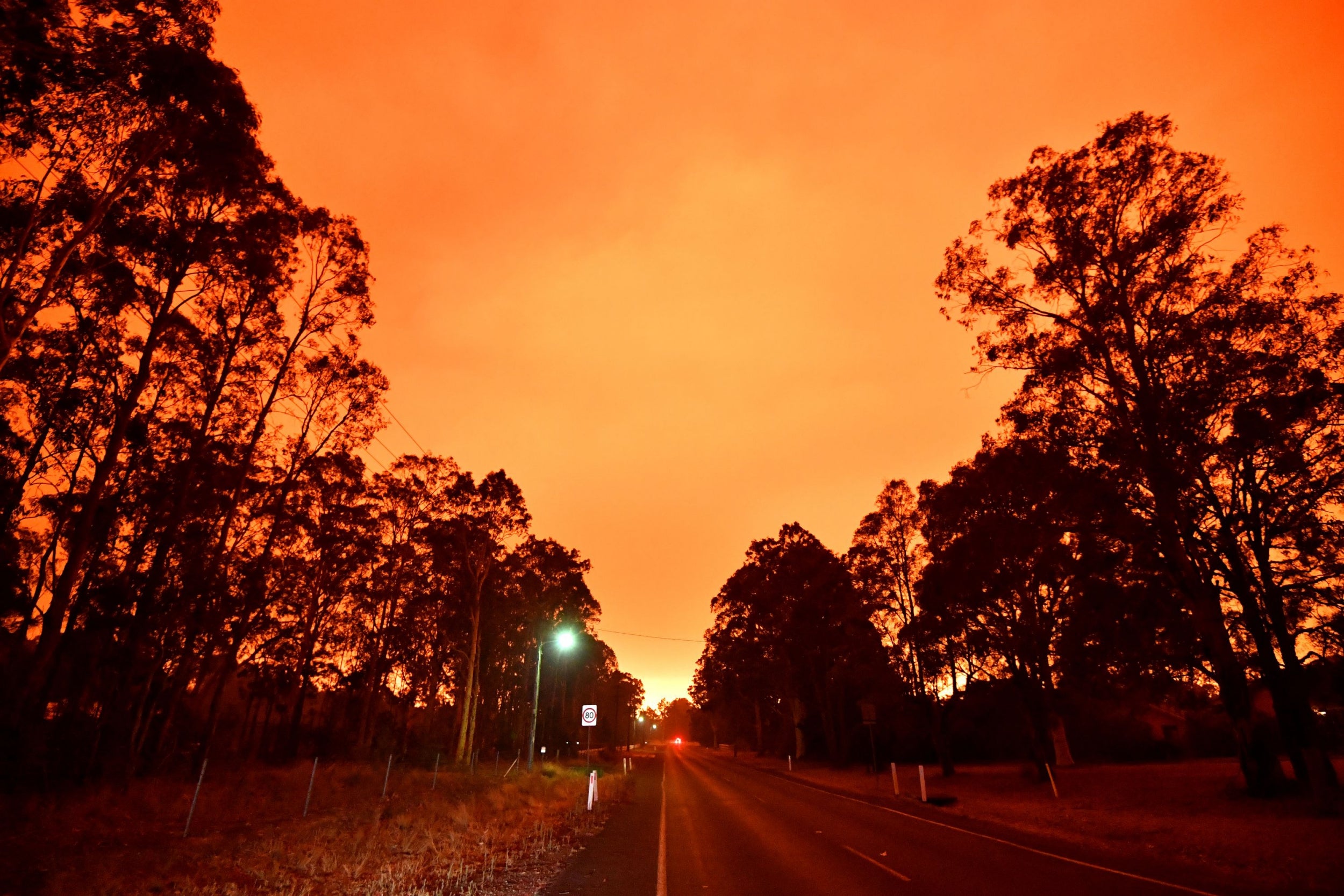 The afternoon sky glows orange from bushfires in the area around the town of Nowra, New South Wales