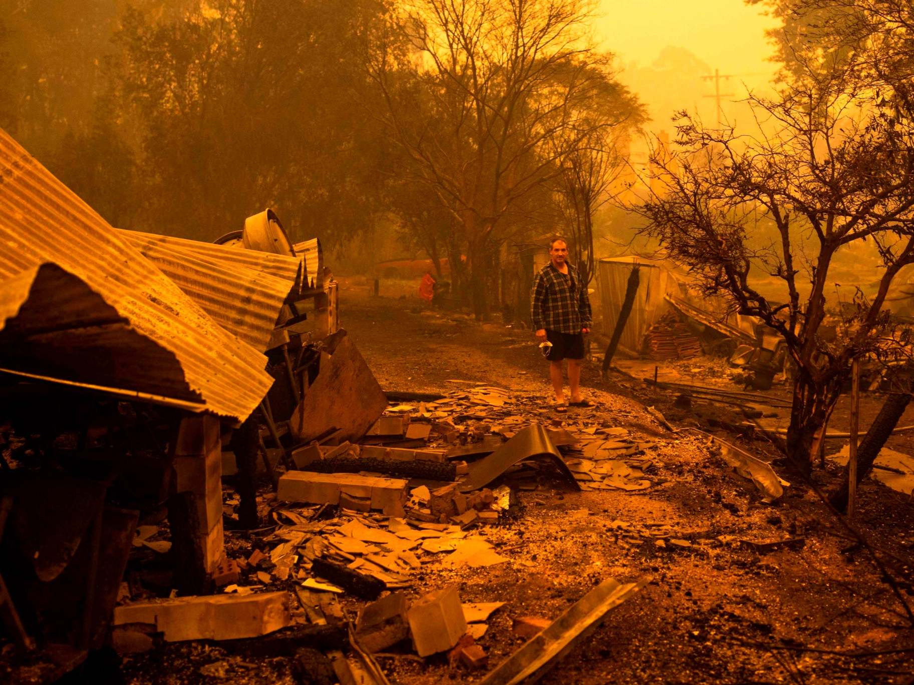A resident stands among rubble after fires devastated the New South Wales town of Cobargo