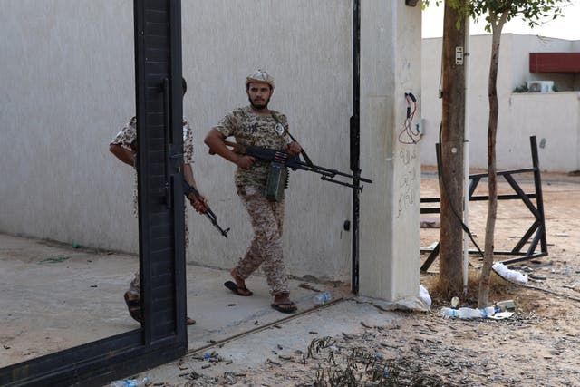 Members of Libya's internationally recognised government forces carry weapons in Ain Zara, Tripoli, in October