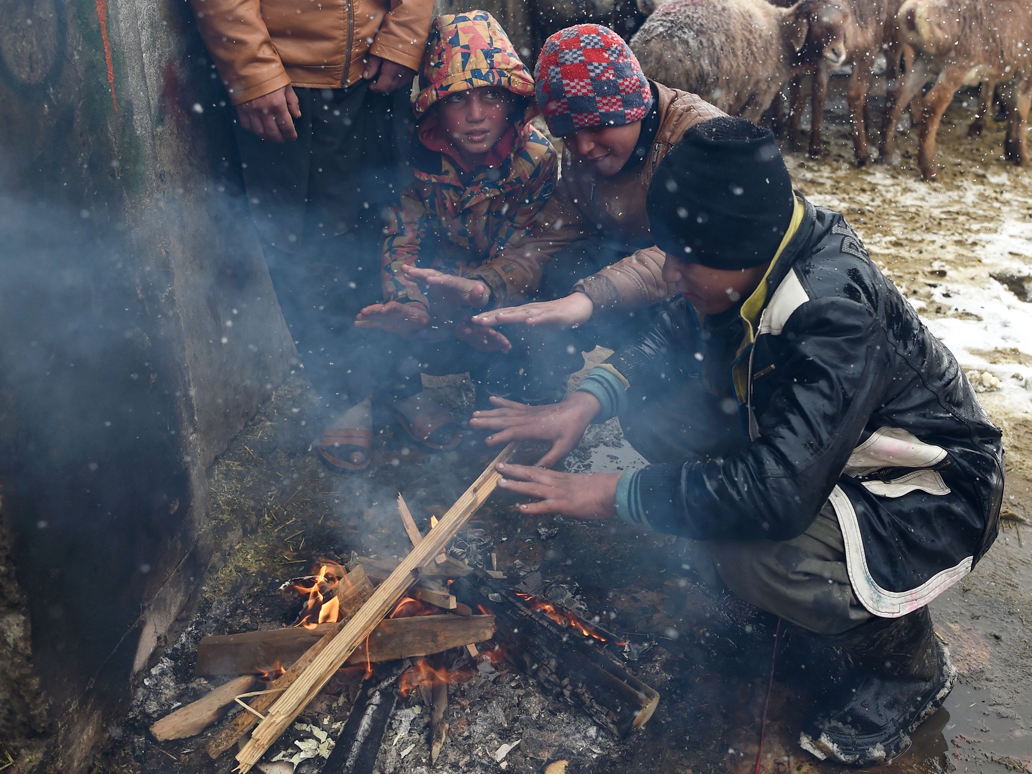 Vendors warm themselves up around a fire as they wait for customers