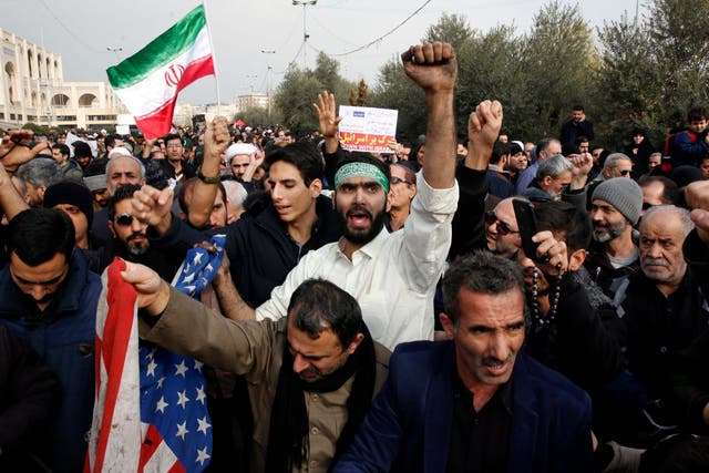 Iranians deface a US flag as thousands of people take to the streets to mourn the death of Soleimani