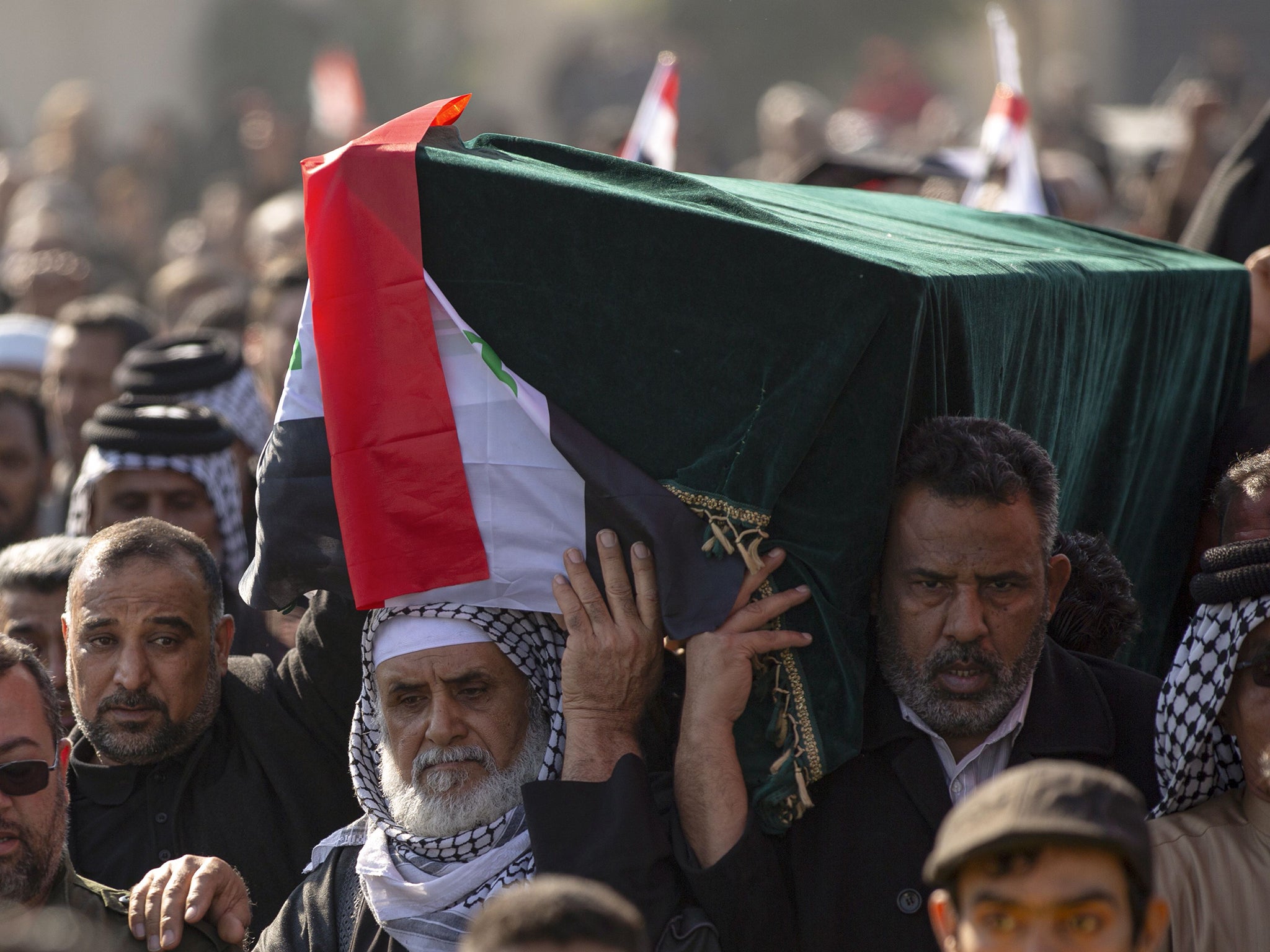 Iraqis carry a mock coffin as they march in a symbolic funeral procession