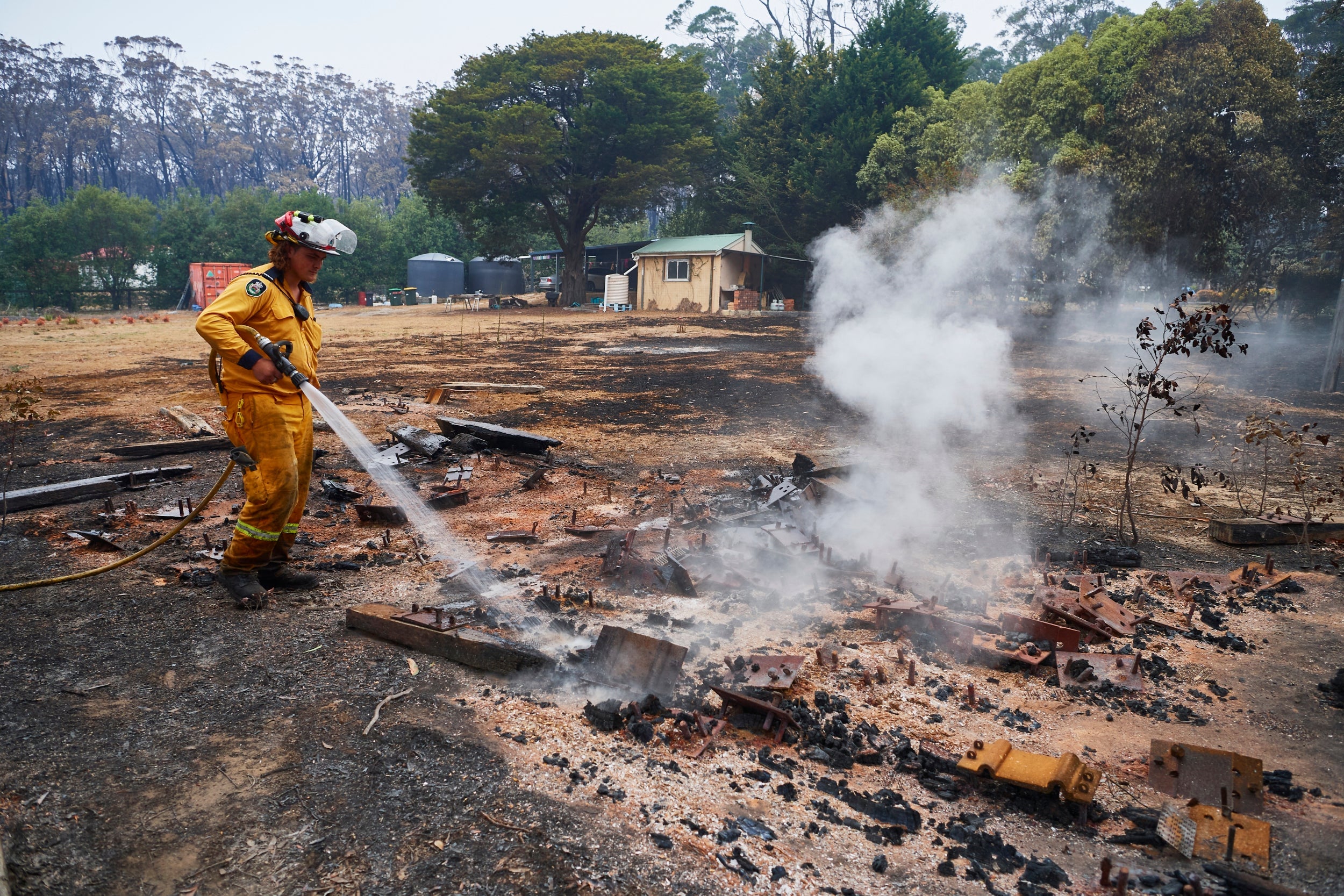 An RFS Crew attempts to put out a smoldering pile of railway sleepers. The sleepers measured over 600 degrees on a thermal temperature gauge two days after the fire front had passed through on 6 January